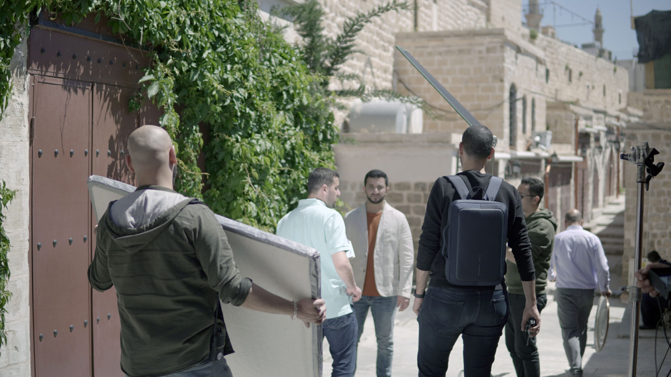 A film crew are talking to a man in a white jacket