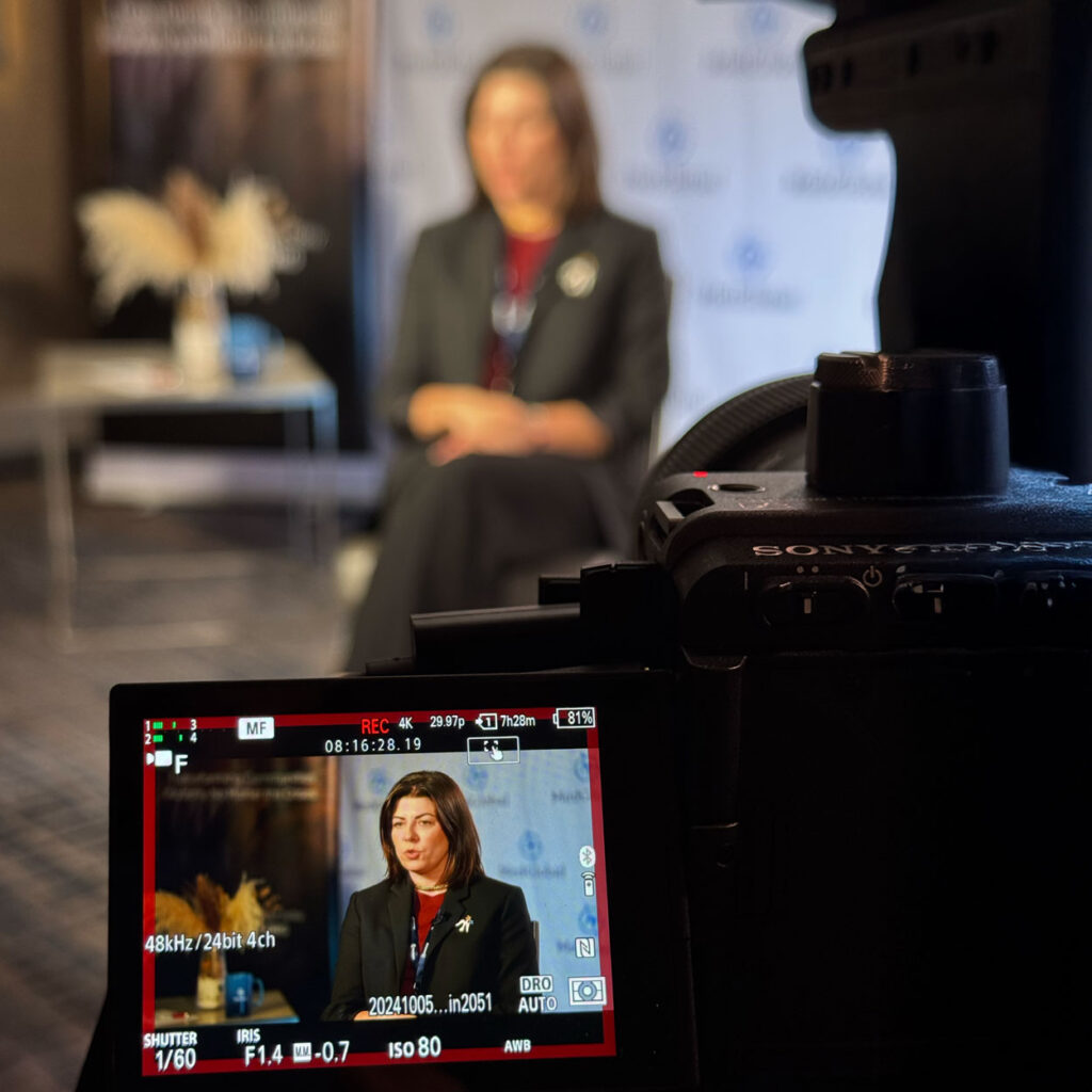 A woman in a red and black suit is shown in the foreground of a camera